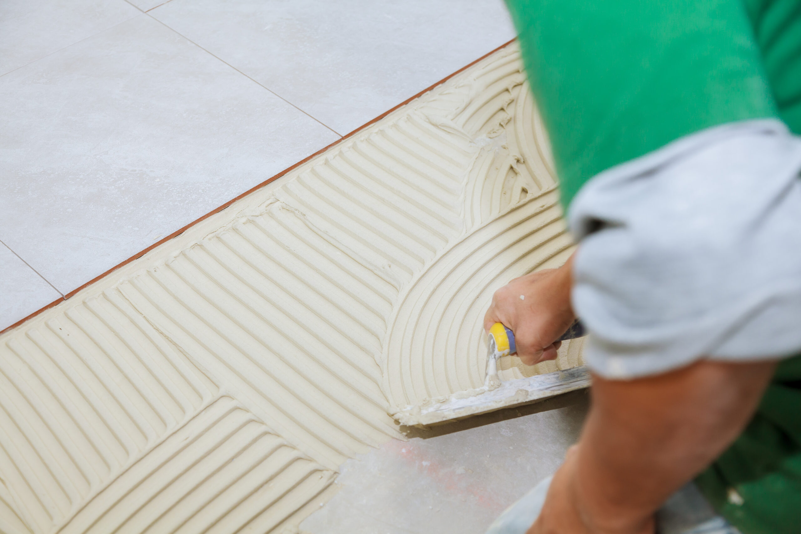 worker-installs-tiles-floor-he-put-glue-using-comb-trowel-master-puts-adhesive